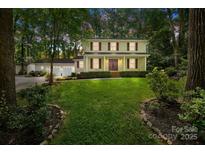 Charming two-story home with a manicured lawn, lush landscaping, and a detached garage with ample parking at 201 Scalybark Trl, Concord, NC 28027