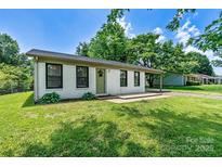Charming white brick home featuring a welcoming green door and a convenient covered parking area at 413 Picadilly Ln, Troutman, NC 28166