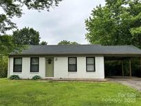 Charming single-story home featuring a carport, freshly painted white brick, and a well-maintained green lawn at 413 Picadilly Ln, Troutman, NC 28166