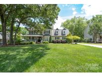 Traditional two-story home featuring a large front yard, covered porch, mature trees, and inviting curb appeal at 503 New Castle Ne Ct, Concord, NC 28025