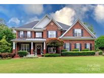 Charming two-story red brick home featuring a well-manicured lawn and inviting front porch at 6202 Pumpernickel Ln, Wesley Chapel, NC 28110