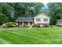 Charming home with a manicured lawn, mature trees, and a welcoming front entrance at 6208 Rocky Falls Rd, Charlotte, NC 28211