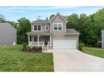 Charming two-story home features a covered porch, attached two car garage, and well-manicured lawn at 7308 Rothmore St, Charlotte, NC 28215