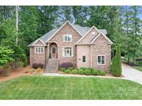 Charming brick home with a well-manicured lawn, mature trees, and inviting front entrance at 7738 Burning Ridge Dr, Stanley, NC 28164
