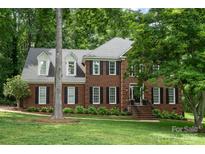 Charming two-story brick home with black shutters and a well-manicured lawn nestled among mature trees at 915 Waterview Ln, Monroe, NC 28110