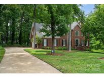 Two story brick home with a well manicured lawn and a curved driveway lined with mature trees at 915 Waterview Ln, Monroe, NC 28110