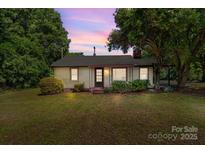 Charming single-story home with a cozy front yard and mature trees under a colorful sunset sky at 94 Sumner Nw Ave, Concord, NC 28027