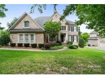 Charming brick home with manicured landscaping, mature trees, and a well-maintained lawn at 9433 Wallace Pond Dr, Huntersville, NC 28078