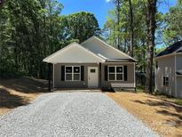 Charming one-story home features gray siding, black shutters, crisp white trim, and a gravel driveway at 001 West Ave, Wadesboro, NC 28170