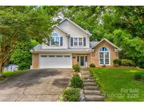 Charming two-story home with a well-manicured lawn, brick accents and a two-car garage, surrounded by lush trees at 1066 Iveywood Nw Pl, Concord, NC 28027