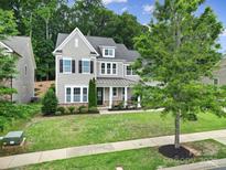 Charming two-story home with a manicured lawn and a welcoming front porch, perfect for relaxing and enjoying the outdoors at 11216 Preservation Ln, Charlotte, NC 28278