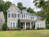 Charming two-story home featuring neutral siding, black shutters, covered porch and lush, well-maintained landscaping at 11216 Preservation Ln, Charlotte, NC 28278