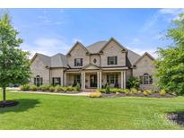 Impressive two-story brick home with a manicured lawn and covered front porch at 1152 Grand Oak Dr, Waxhaw, NC 28173