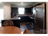 Modern kitchen features black cabinets, stainless steel appliances, and granite countertops at 116 Crownpiece St, Troutman, NC 28166