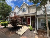 Charming townhome with red door, covered porch, well-manicured landscaping, and inviting curb appeal at 12238 Paperbark Cir, Charlotte, NC 28277
