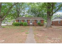 Charming brick home with black shutters, lush trees, and a walkway leading to the front door at 1320 Hartford Ave, Charlotte, NC 28209
