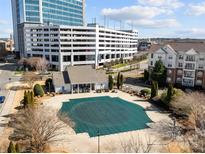 Aerial view of a community pool with a protective green cover, surrounded by buildings in a landscaped environment at 14853 Santa Lucia Dr, Charlotte, NC 28277