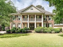 Elegant brick home with white columns, second story balcony, and manicured front lawn at 18419 Dembridge Dr, Davidson, NC 28036