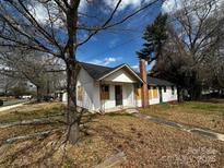 Modest single-story house with white siding and a brick chimney, ready for renovation and new beginnings at 306 E Arch St, Lancaster, SC 29720