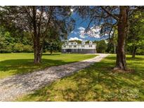Inviting home featuring a gravel driveway, expansive lawn, and mature trees against a blue sky backdrop at 330 Skyview Dr, Catawba, SC 29704