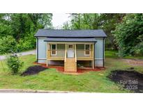 Charming cottage-style home featuring a cozy porch with wooden railing and fresh landscaping at 18 S Coulter Ave, Newton, NC 28658