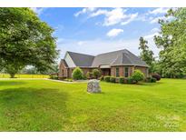 A charming brick home features a well-manicured lawn, mature trees, and lovely landscaping at 1825 Smyre Farm Rd, Newton, NC 28658