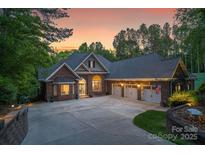 Stunning brick home with a three-car garage and a circular driveway at dusk at 2200 Capes Cove Dr, Sherrills Ford, NC 28673