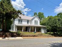 Two-story home with metal roof and covered front porch, nestled under mature trees at 273 E Main Ave, Taylorsville, NC 28681