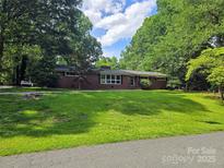 Charming brick home with lush front lawn and mature trees offering privacy and curb appeal at 520 Crestview Dr, Albemarle, NC 28001