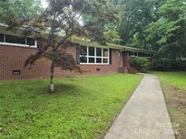 Charming brick home featuring a well-manicured lawn, and a walkway leading to the front door at 520 Crestview Dr, Albemarle, NC 28001
