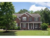 Charming two-story brick home featuring classic shutters, a covered front porch, and a well-manicured lawn at 6309 Crosshall Pl, Waxhaw, NC 28173