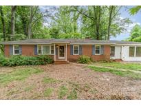 Cozy brick home featuring blue shutters and a charming front yard surrounded by mature trees at 6934 Lockhart Rd, Sharon, SC 29742