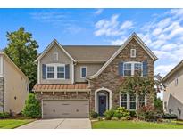 Charming two-story home boasts stone accents, blue shutters, and manicured landscaping at 9750 Briarwick Ln, Charlotte, NC 28277