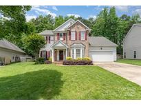 Charming two-story home featuring brick accents, red shutters, and a well-manicured lawn at 10322 Stoneykirk Ln, Charlotte, NC 28269