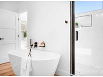 Bright bathroom with a modern soaking tub, glass shower, and sleek black fixtures at 104 Arbor Dr, Waxhaw, NC 28173
