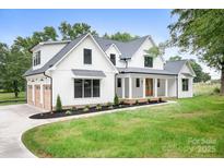 Beautiful two-story modern farmhouse with white siding, dark roof, and a welcoming front porch at 104 Arbor Dr, Waxhaw, NC 28173