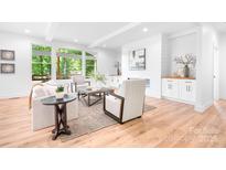 Bright living room with white walls, wood floors, fireplace, and large windows with a view of the outdoor deck at 104 Arbor Dr, Waxhaw, NC 28173