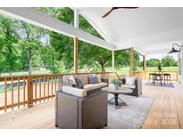 Inviting covered patio featuring wicker furniture, ceiling fan, and view of the lush backyard at 104 Arbor Dr, Waxhaw, NC 28173