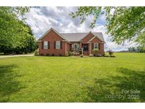 Charming red brick home with manicured lawn and landscaping under a partly cloudy sky at 1111 Lizzie Ln, Salisbury, NC 28147