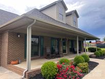 Charming brick home featuring a spacious front porch with rocking chairs and beautiful landscaping at 1351 Hardin Rd, Dallas, NC 28034