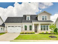 Charming two-story home with a manicured lawn, attached garage, and inviting front porch at 13702 Tranquil Day Dr, Matthews, NC 28105