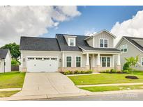 Charming home with two-car garage, dormer window, landscaping, and a covered porch at 13702 Tranquil Day Dr, Matthews, NC 28105