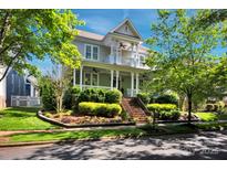 Inviting two-story home with covered porch, landscaped yard, and mature trees under a sunny sky at 15430 Waterfront Dr, Huntersville, NC 28078