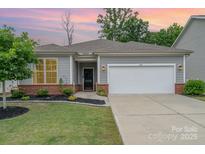 Charming single-story home with a two-car garage, manicured lawn, and brick accents at dusk at 1813 Shelbourne Way, Fort Mill, SC 29707