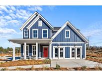Charming two-story blue home with white trim, a red front door, and well-manicured landscaping at 2004 Waxhaw Crossing Dr, Waxhaw, NC 28173