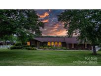 Charming brick home featuring a well-manicured lawn and beautiful landscaping under an orange sunset at 2448 Moss Farm Rd, Hickory, NC 28602