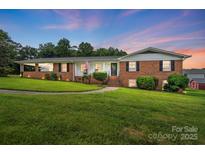 Charming brick home with manicured lawn, welcoming front porch, and patriotic American flag at 2968 Grace St, Claremont, NC 28610