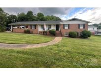 Charming brick home featuring a well-manicured lawn, covered side porch, and inviting front entrance at 2968 Grace St, Claremont, NC 28610
