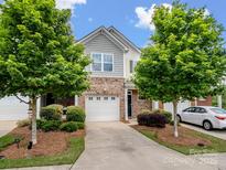 Charming townhome showcasing manicured landscaping, neutral brick, and a driveway leading to the attached garage at 3306 Yarmouth Ln, Gastonia, NC 28056