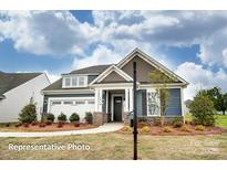 Charming single-Gathering home with blue siding, stone accents, and a well-manicured front lawn at 3315 Whispering Creek Dr # 95, Wesley Chapel, NC 28079